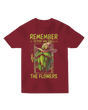 "White ‘Remember to Stop and Smell’ t-shirt with abstract daisy graphic, modeled in a sunflower field for nature-inspired humor"